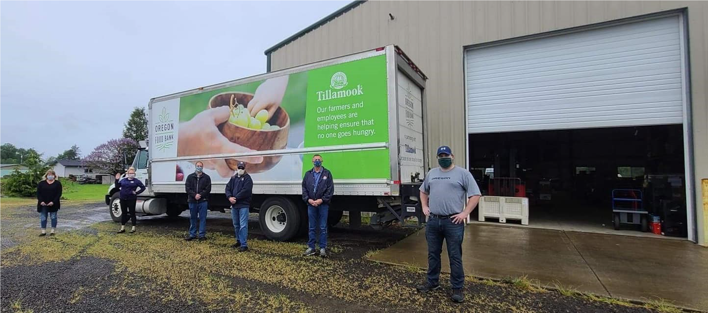 Image of five people, the Tillamook team, standing in front of a large box truck with the text 