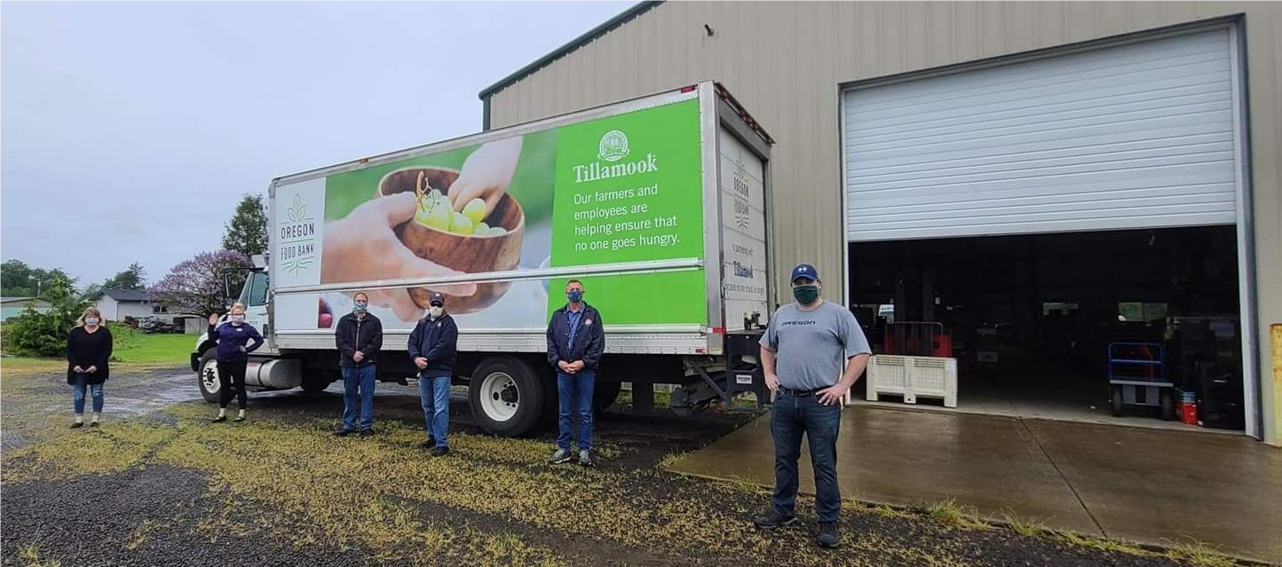 Image of five people, the Tillamook team, standing in front of a large box truck with the text