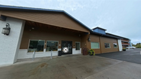 Photo of the entry to a large, brown apartment building. This is the Hawk's Eye Apartments in Seaside, Oregon